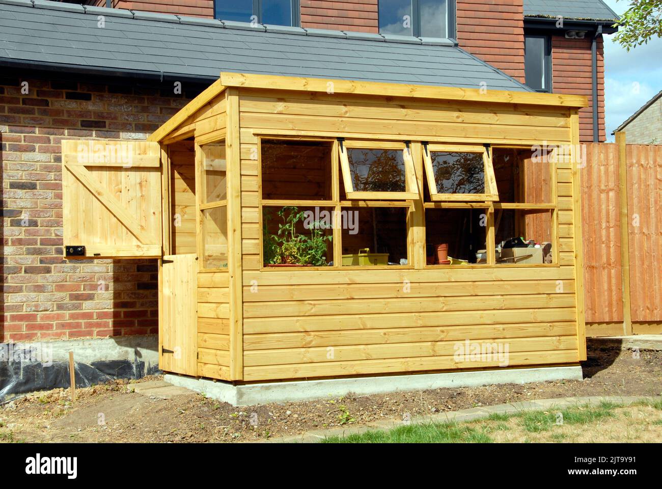 Hangar en pot de jardin en bois avec fenêtres ouvertes et porte stable ouverte Banque D'Images