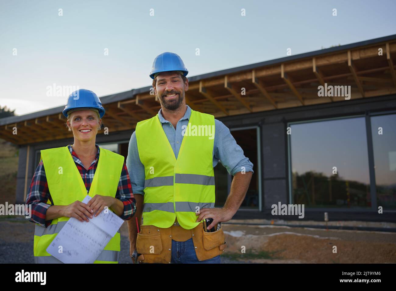 Des ingénieurs de construction ou des architectes avec des plans-plans visitant le site de construction écologique de la maison de cadre en bois Banque D'Images