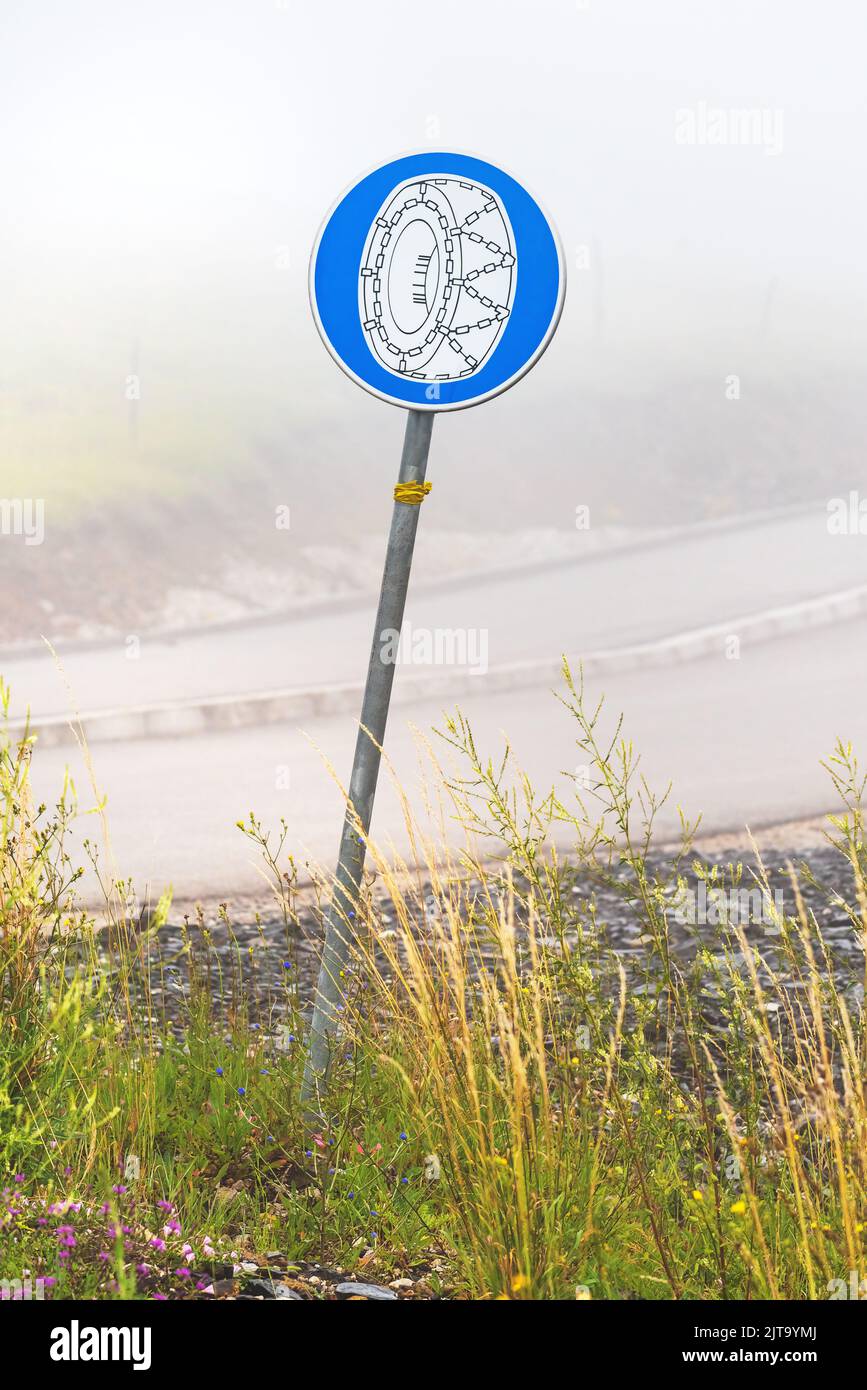 Signalisation routière obligatoire sur les roues à chaîne de neige en hiver sur le matin froid brumeux, attention sélective Banque D'Images Signalisation routière obligatoire sur les roues à chaîne de neige en hiver sur le matin froid brumeux, attention sélective Banque D'Images