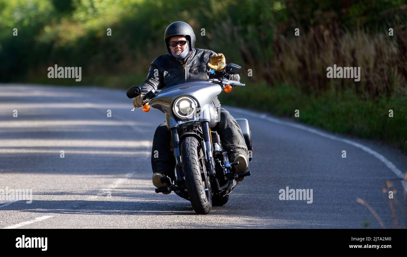Homme à bord d'une moto Harley Davidson sur une route de campagne anglaise Banque D'Images