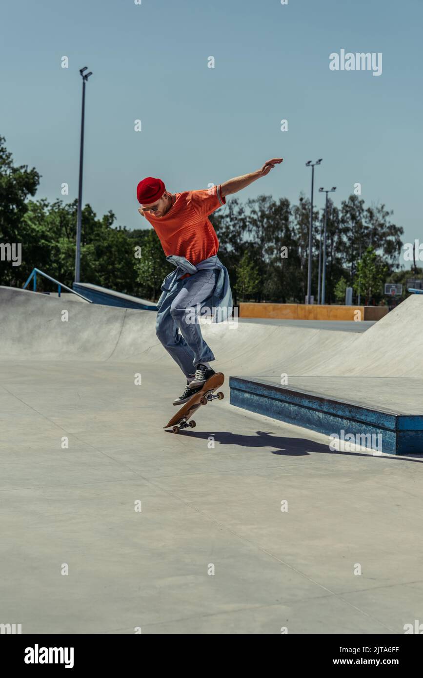 jeune homme dans une tenue d'été tendance sautant avec un skateboard Banque D'Images