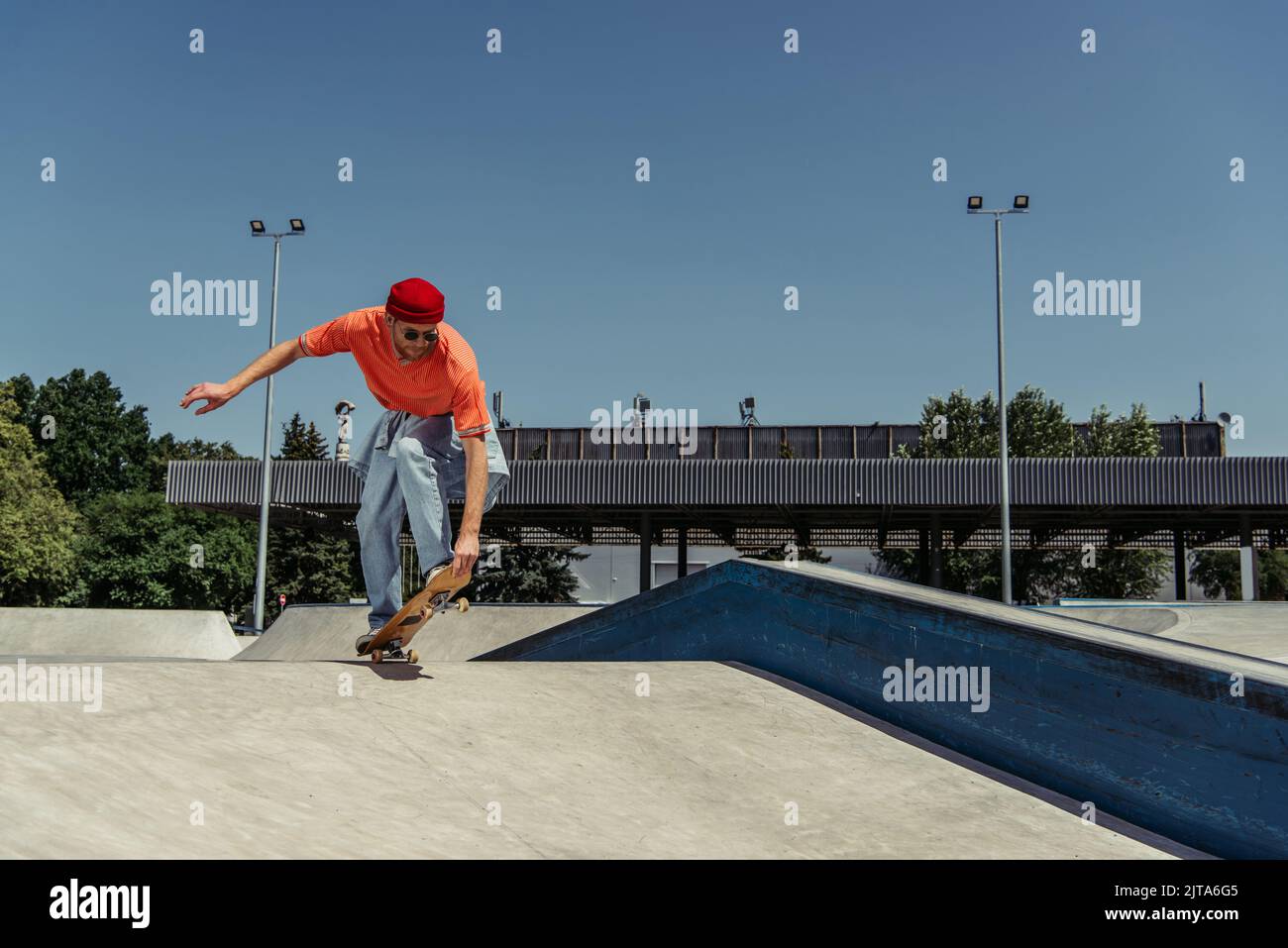 jeune homme en vêtements élégants skate sur la rampe dans le parc Banque D'Images