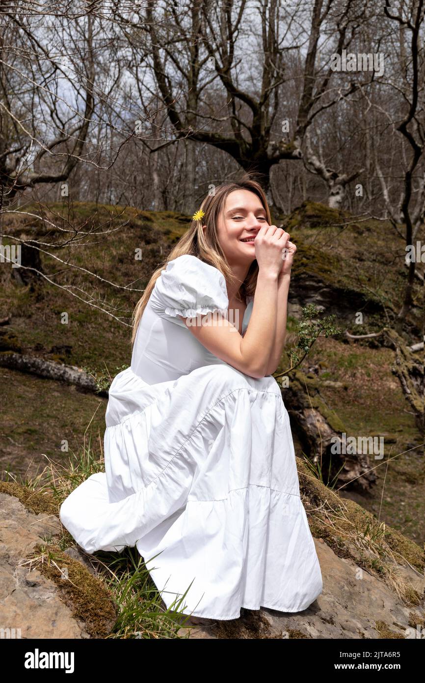 femme en robe blanche assise dans la forêt pensive Banque D'Images