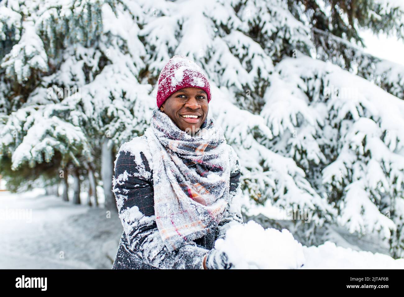 homme afro-américain dans une forêt enneigée d'hiver avec des flocons de neige tombant de forêt d'épinette et de sapin Banque D'Images