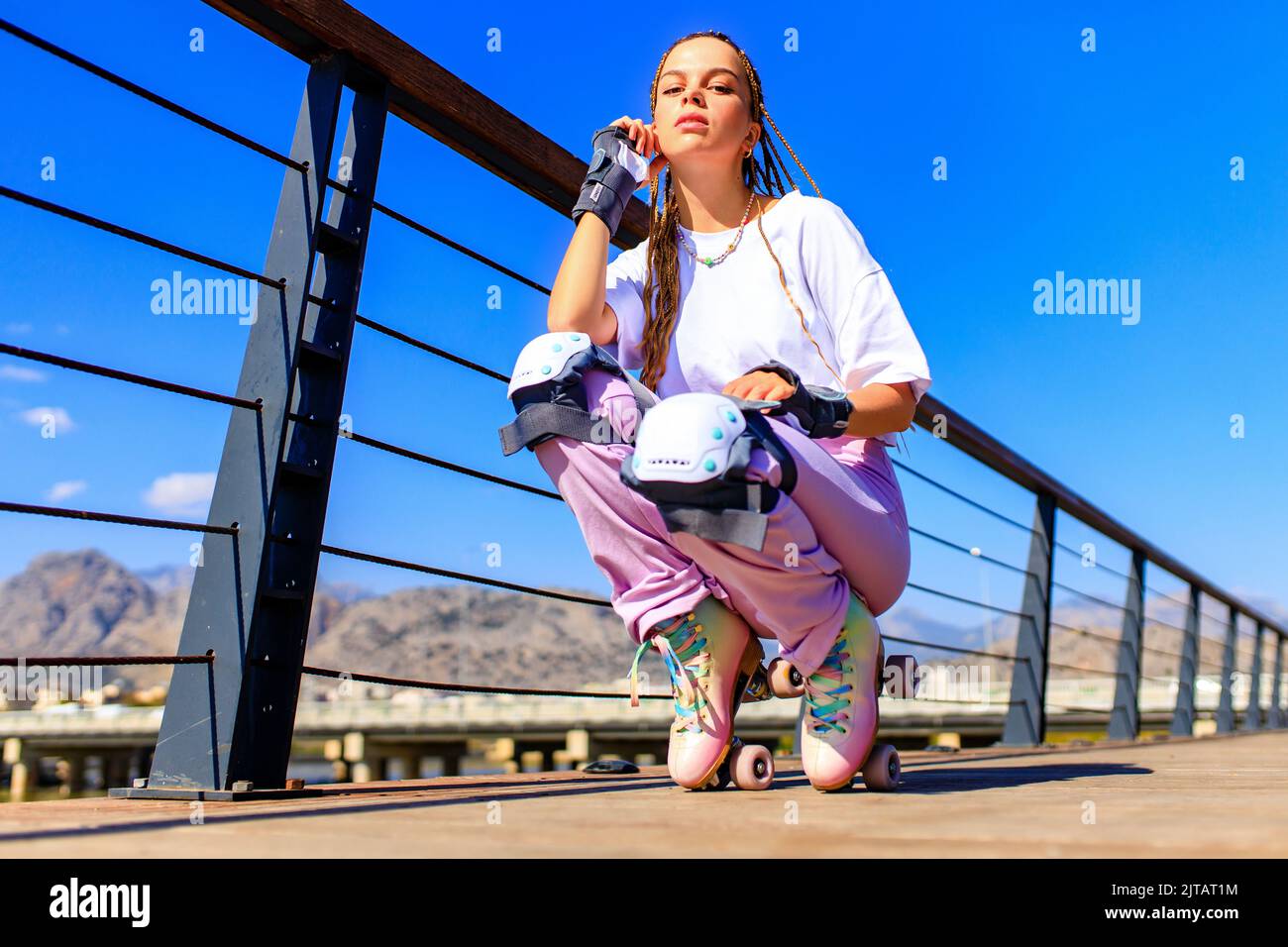 Femme heureuse avec de longs cheveux blonds sur le roller-skate sur la plage du parc et le fond de la montagne Banque D'Images Femme heureuse avec de longs cheveux blonds sur le roller-skate sur la plage du parc et le fond de la montagne Banque D'Images