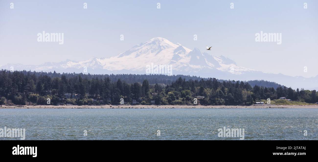 Maisons au bord de la plage sur la côte ouest de l'océan Pacifique avec montagne enneigée Banque D'Images
