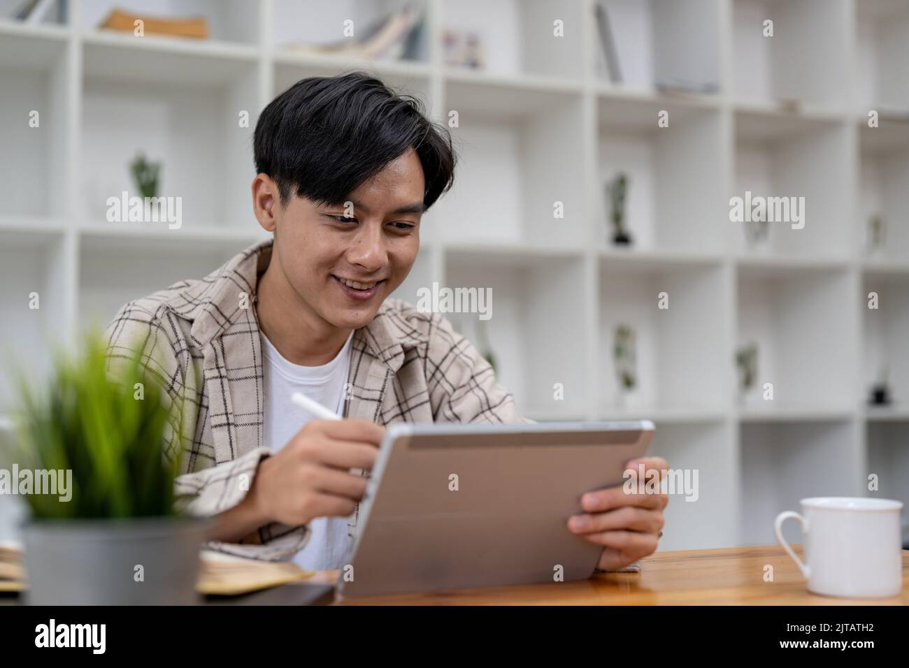 Jeunes étudiants asiatiques qui utilisent une tablette numérique pour étudier à distance, regarder un webinaire en ligne, effectuer un zoom sur la formation virtuelle lors d'une réunion par vidéoconférence. Banque D'Images