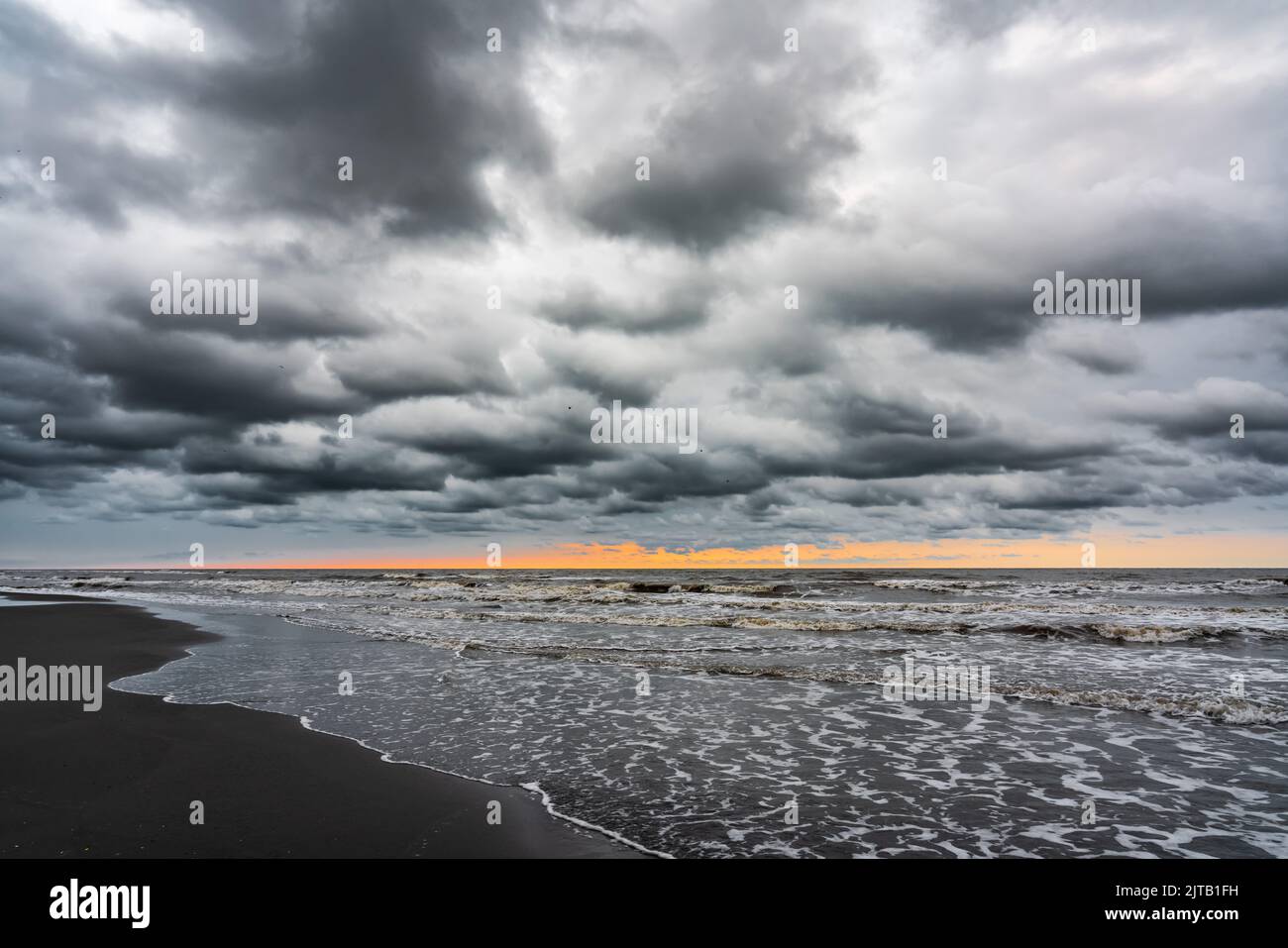 Vagues sur la plage de la mer par un jour pluvieux nuageux Banque D'Images