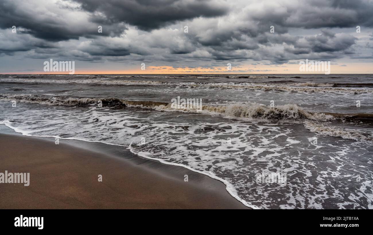 Vagues sur la plage de la mer par un jour pluvieux nuageux Banque D'Images