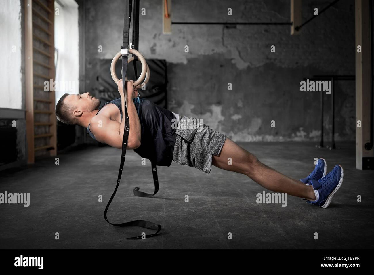 homme faisant de l'exercice sur les anneaux de gymnastique en salle de gym Banque D'Images