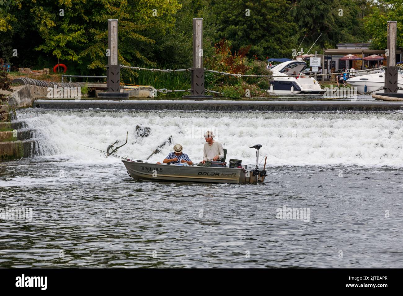 Deux hommes dans un petit bateau pêchant sous un déversoir sur la Tamise en été Banque D'Images