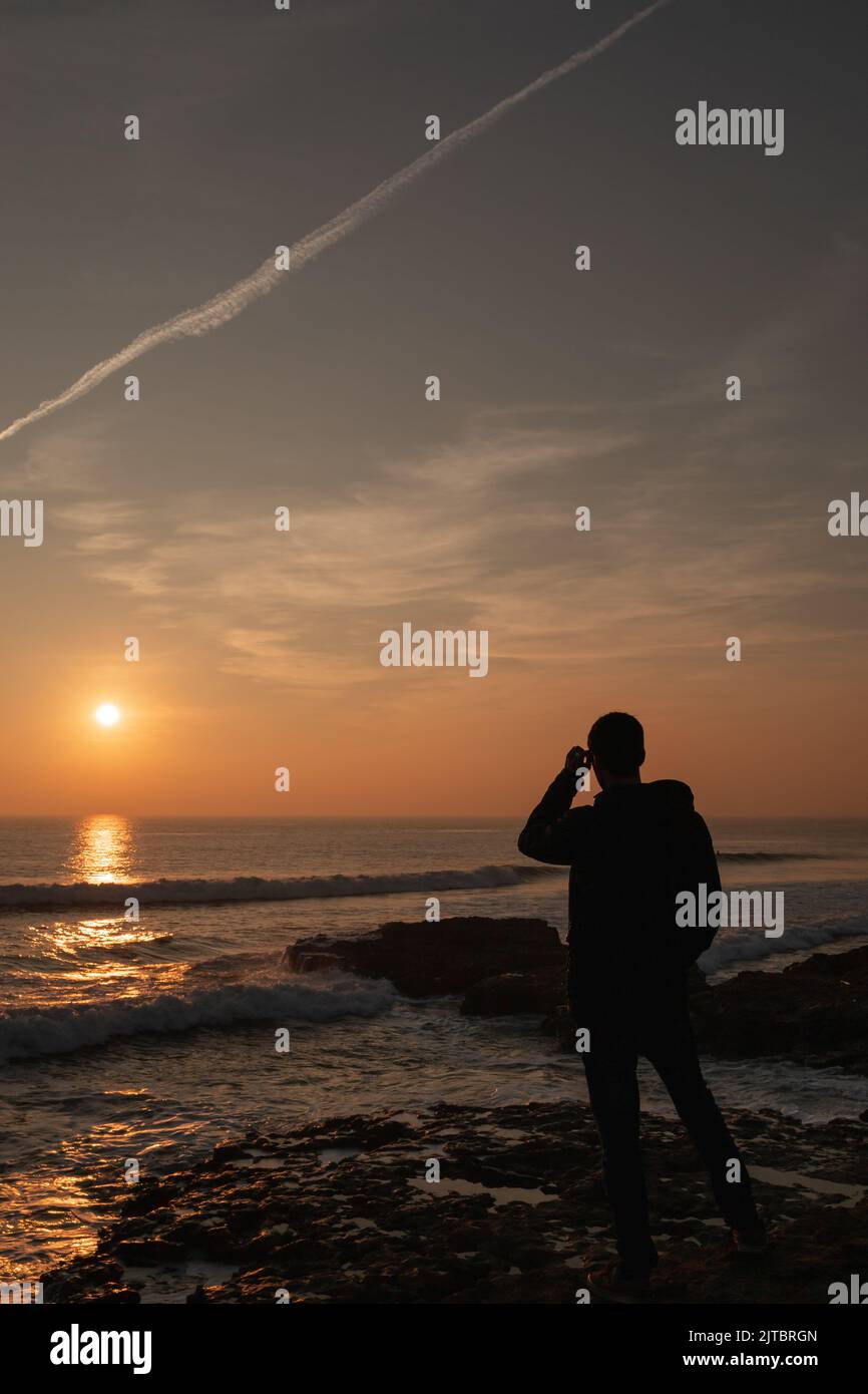 Une silhouette d'homme regardant un coucher de soleil panoramique sur l'océan Atlantique au Portugal Banque D'Images