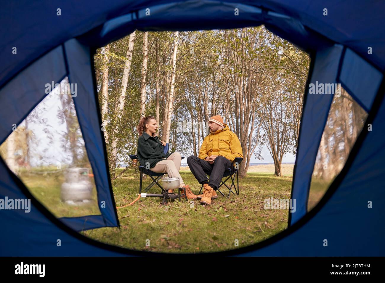 couple cuisine de la nourriture au camp de tente et de parler Banque D'Images