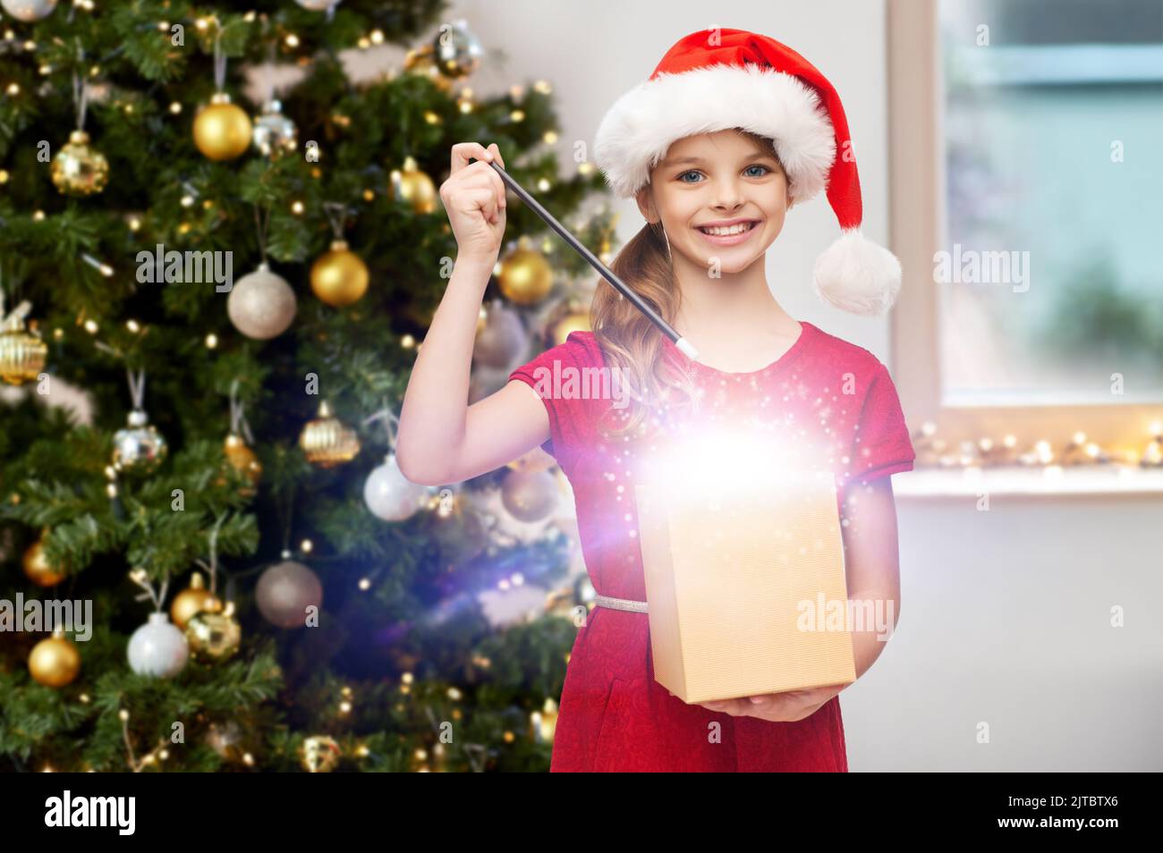 fille souriante avec baguette magique et cadeau de noël Banque D'Images