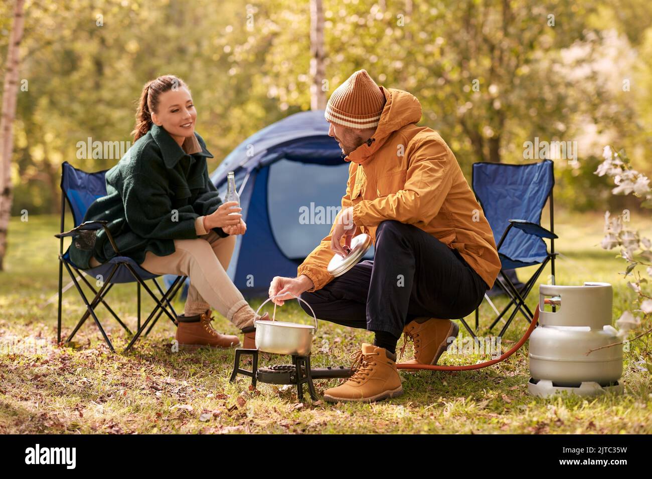 couple de boire de la bière et de la nourriture de cuisine au camp de tente Banque D'Images