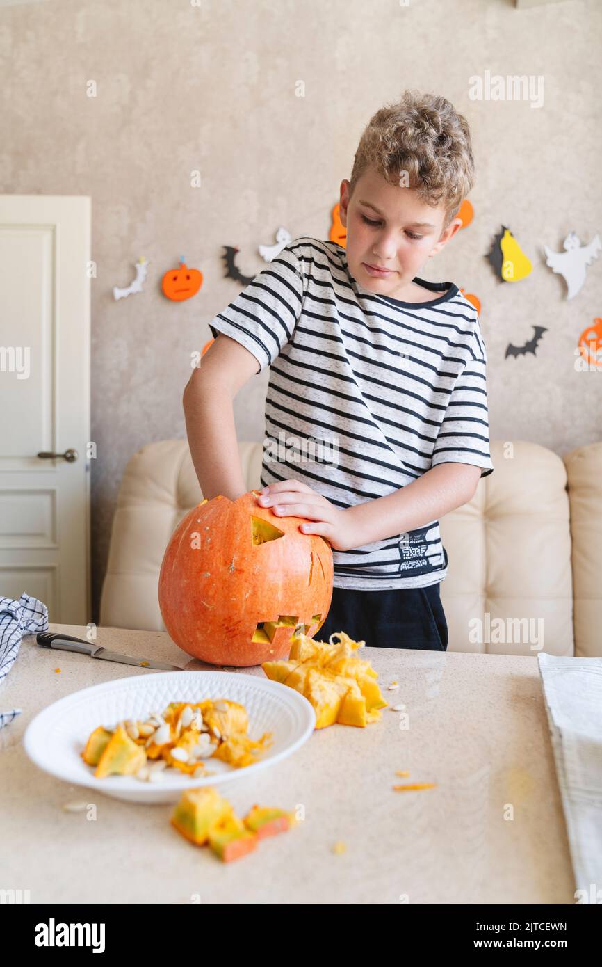 Un garçon coupe une citrouille Jack o lanterne pour Halloween. Banque D'Images