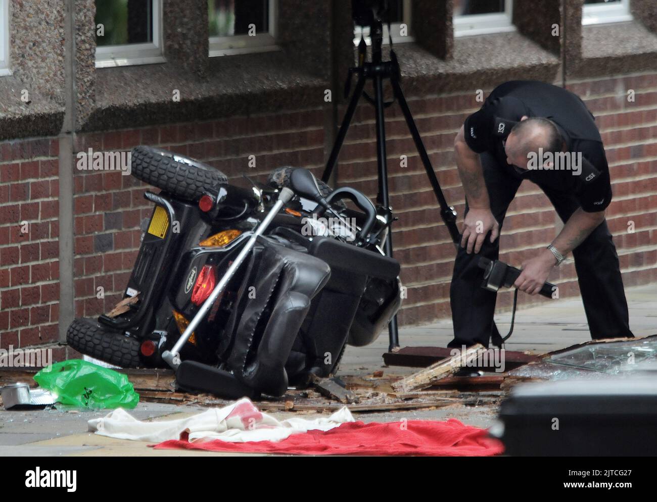 Un policier examine le scooter Qu'Un HOMME est mort après avoir conduit accidentellement son scooter de mobilité à travers une fenêtre en verre il a quitté le centre médical à Osborne Road, Fareham, Hampshire et a conduit à travers des portes doubles en verre avant de tomber 12ft à travers la paroi en verre de la passerelle. L'homme de Fareham, âgé de 82 ans, a été déclaré mort sur les lieux. PHOTO MIKE WALKER, PHOTOS MIKE WALKER, 2012 Banque D'Images