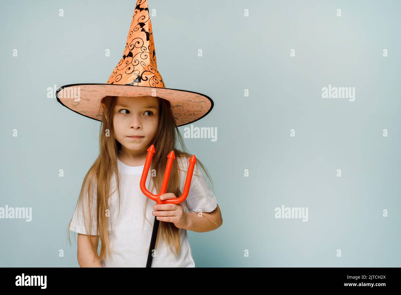 Halloween enfants fille se berner autour avec petit diable trident sur fond bleu avec l'espace de copie. Prêt pour le week-end avec des blagues ou des gâteries. Banque D'Images