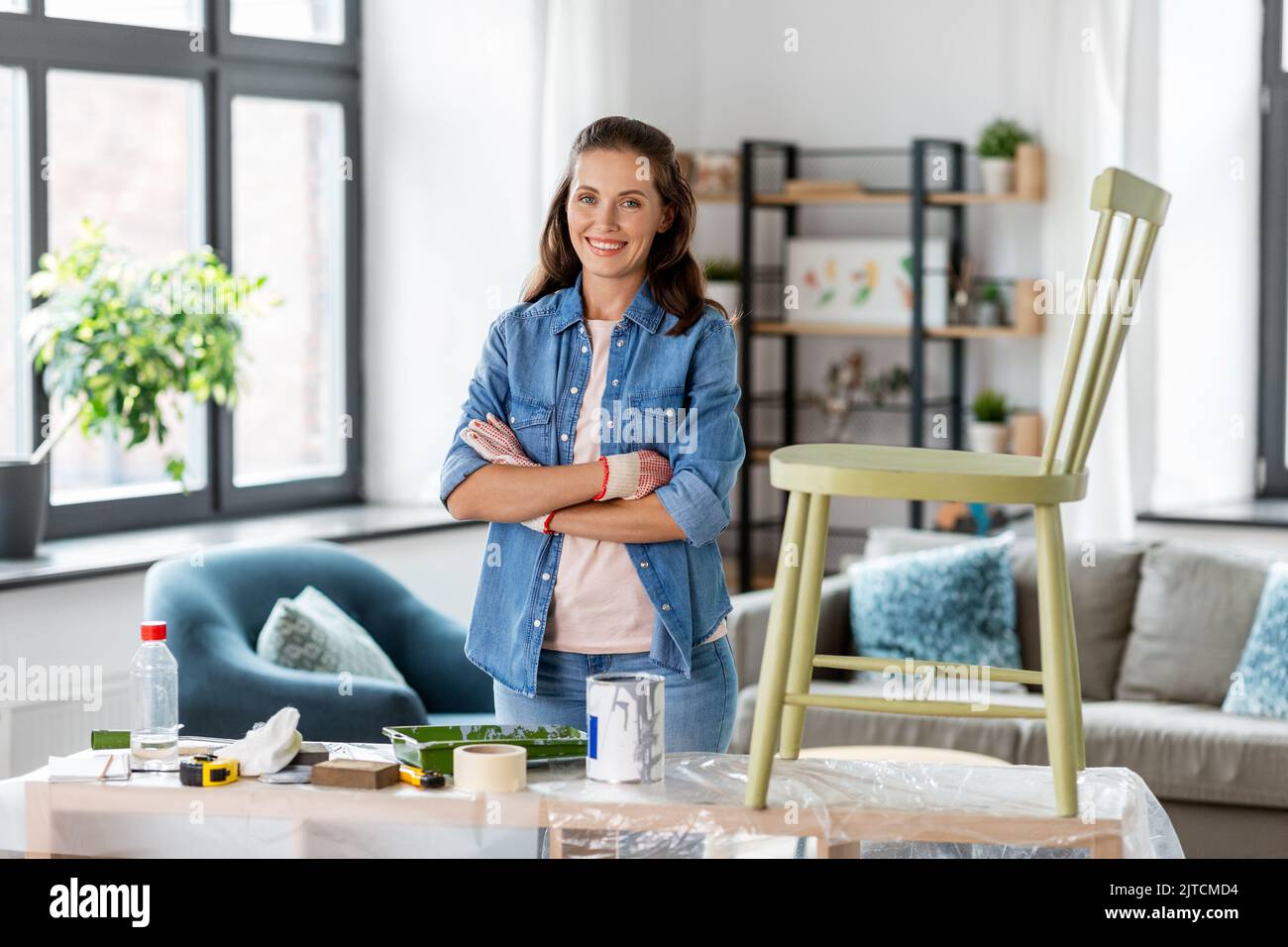 femme heureuse avec bras croisés rénovant la vieille chaise Banque D'Images