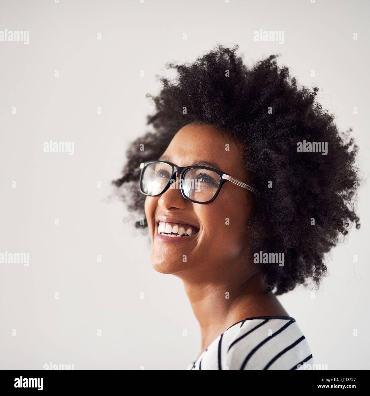 Choisissez le bonheur toute la journée tous les jours. Photo en studio d'une jeune femme attrayante et heureuse portant des lunettes sur fond gris. Banque D'Images