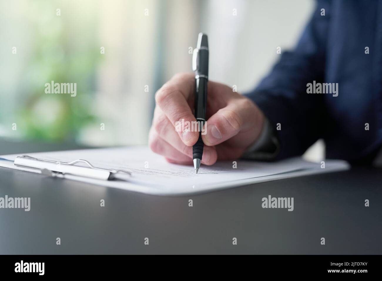 HES a obtenu les réponses : un homme d'affaires a rempli les documents sur une planchette à pince tout en étant assis à une table dans un bureau. Banque D'Images