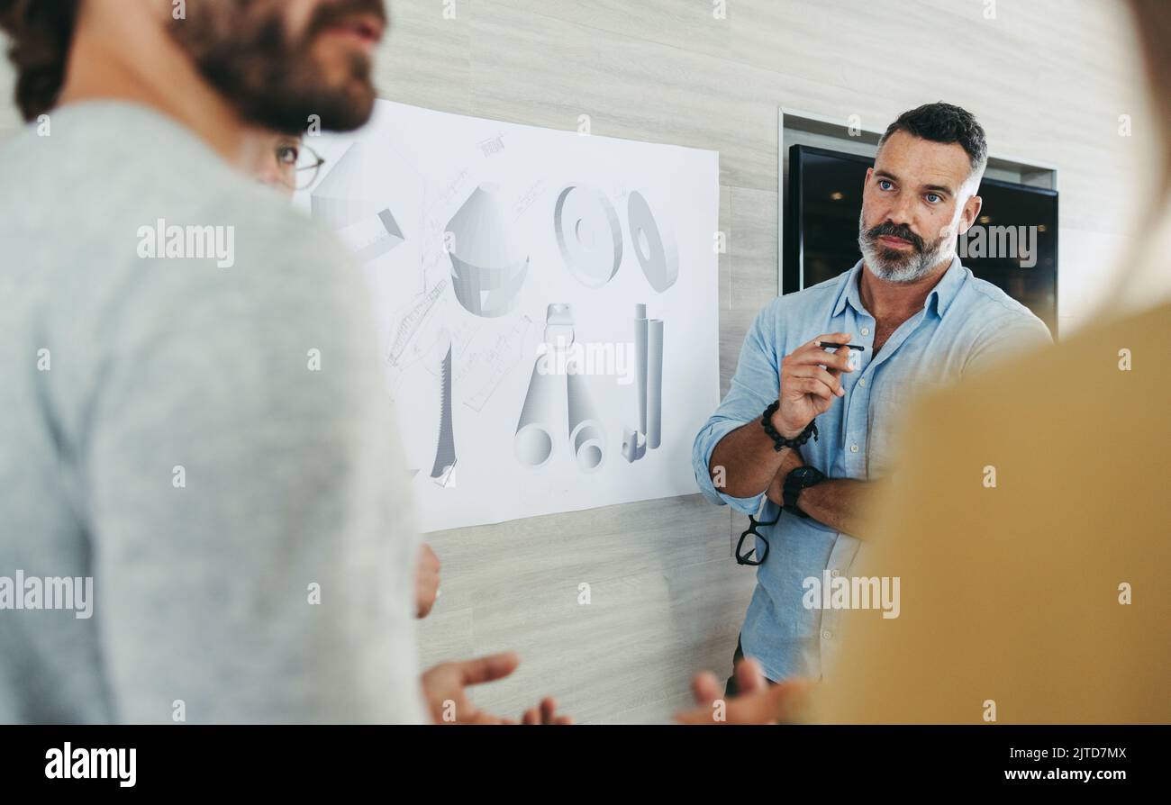Des hommes d'affaires créatifs qui ont une discussion tout en travaillant avec des dessins de conception dans un bureau moderne. Groupe de concepteurs innovants prévoyant un renouvelable Banque D'Images
