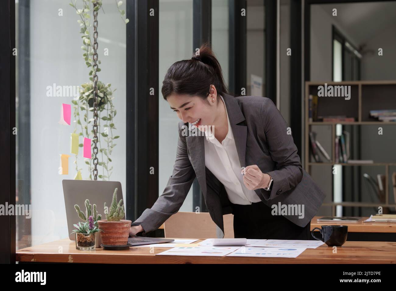 Bonne femme asiatique utilisant un ordinateur portable tout en ayant une bonne nouvelle de travailler au bureau. Banque D'Images