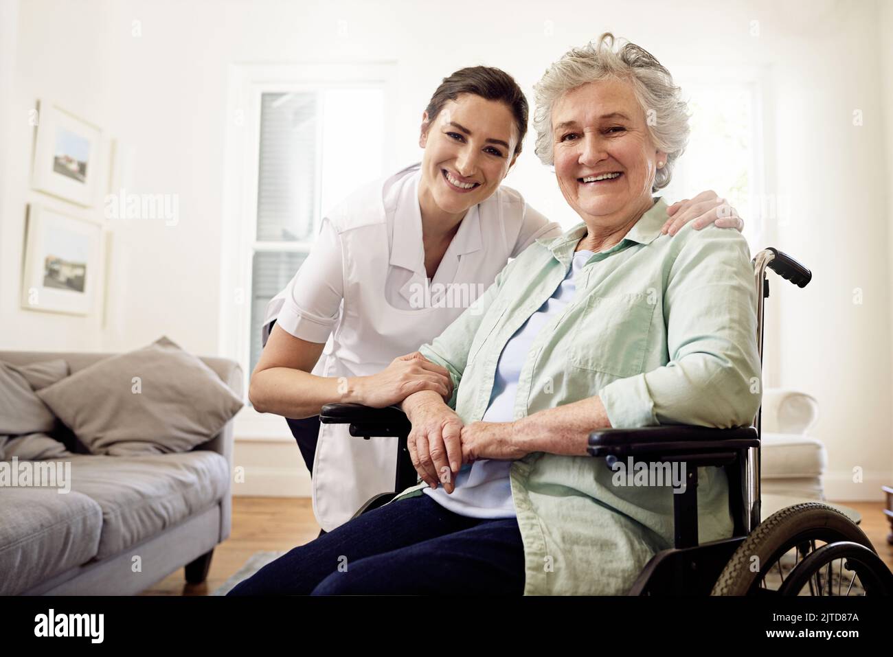 Des shes là pour s'en occuper. Portrait d'un aidant souriant et d'une femme âgée en fauteuil roulant à la maison. Banque D'Images