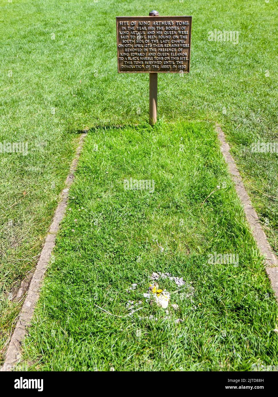 Un panneau dans l'herbe verte marque le site de la tombe du roi Arthur de 1278 à 1539 à Glastonbury, Somerset, Angleterre, Royaume-Uni. Banque D'Images