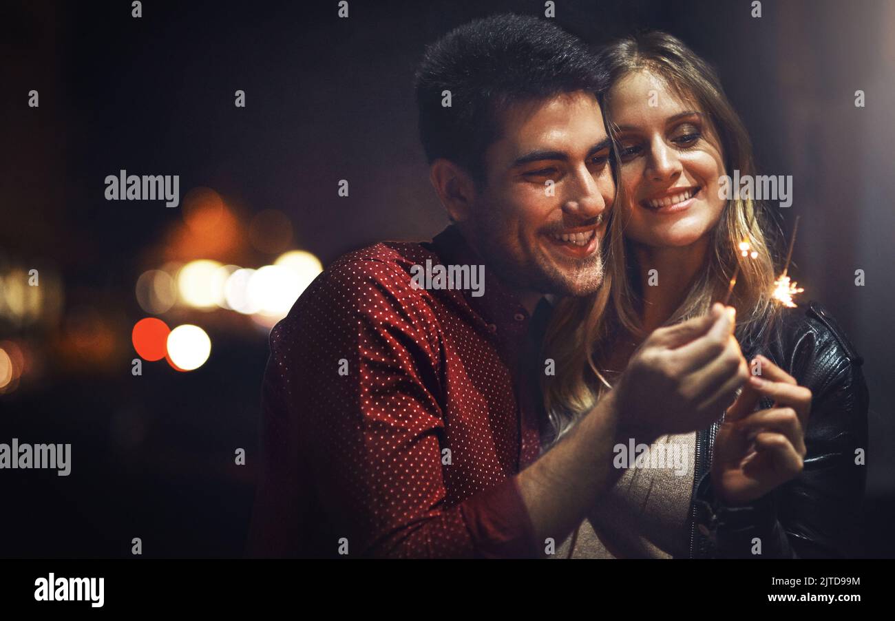 Pour célébrer notre amour... un jeune couple heureux qui fête avec des fêteurs dehors la nuit. Banque D'Images