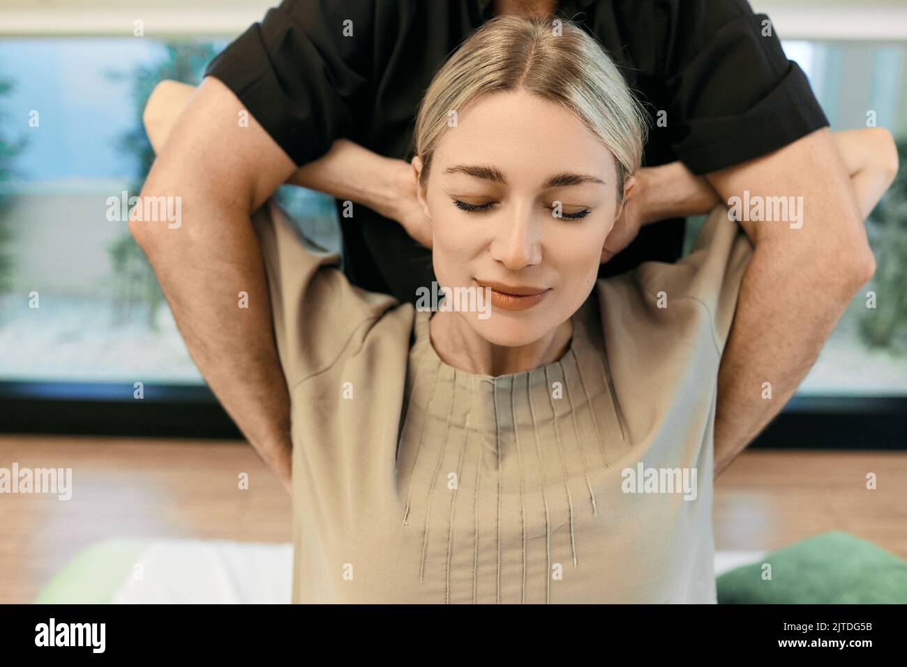 Massage thérapeutique Yumeiho. Massothérapeute effectuant des exercices de récupération pour la patiente avec les mains derrière son cou Banque D'Images