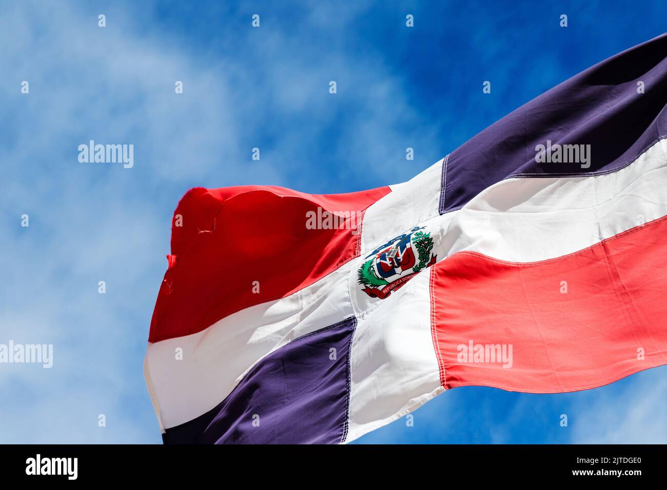 Le drapeau d'Etat de la république dominicaine agite sous un ciel nuageux par une journée ensoleillée, en gros plan Banque D'Images