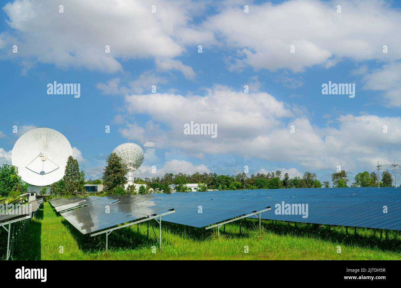Ferme solaire et champ vert avec ciel bleu. Grande parabole satellite près de la ferme solaire. L'énergie solaire pour l'énergie verte. Les centrales photovoltaïques génèrent du solaire Banque D'Images