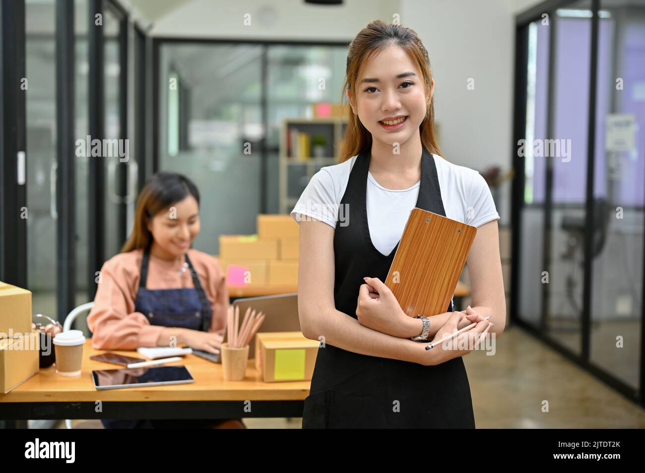 Jeune femme asiatique professionnelle et prospère, entrepreneur en PME ou entreprise de commerce électronique, se tenant devant sa salle des stocks. Banque D'Images