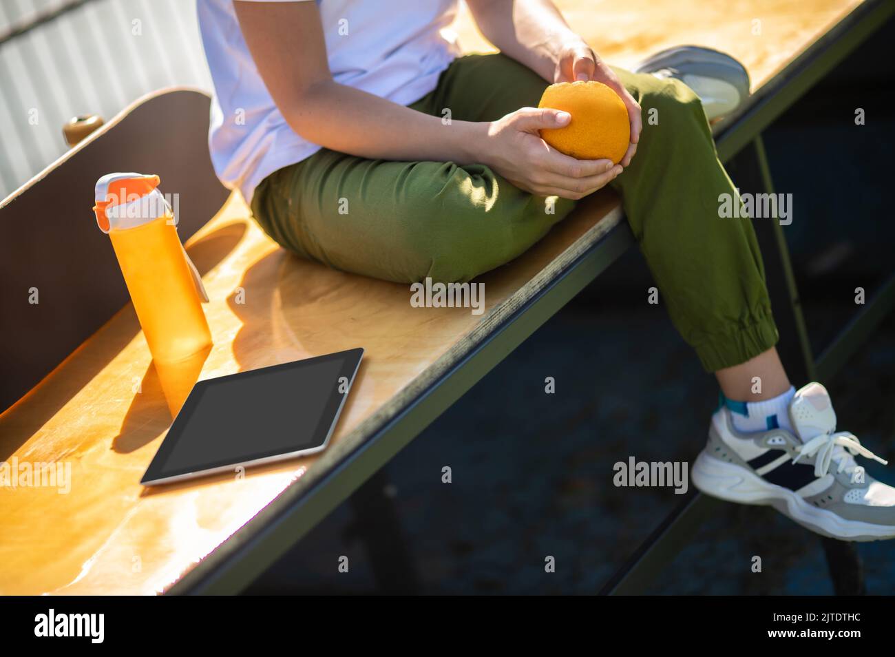 Garçon avec une orange assis dans un café extérieur Banque D'Images