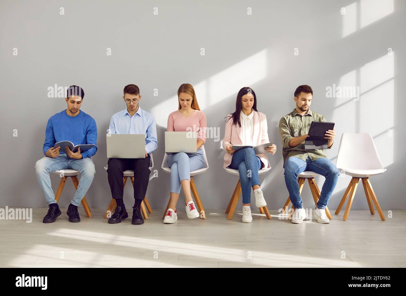 Les jeunes utilisent des ordinateurs portables et des tablettes en attendant des entretiens d'embauche ou des rendez-vous professionnels Banque D'Images