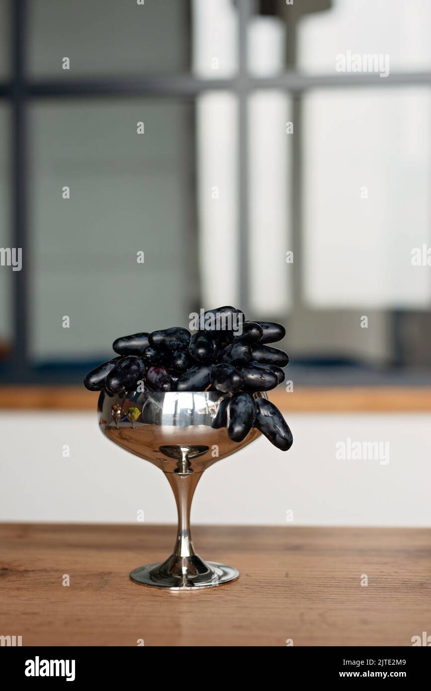 Un bouquet de raisins mûrs bleu foncé dans un bol en métal sur la table. Alimentation, alimentation saine. Mise au point sélective douce. Banque D'Images