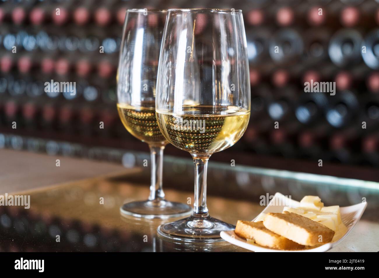 Dégustation de vins dans la cave - 2 verres de vin blanc avec toasts et fromage avec des centaines de bouteilles de vin empilées derrière, Lanzarote, Espagne Banque D'Images
