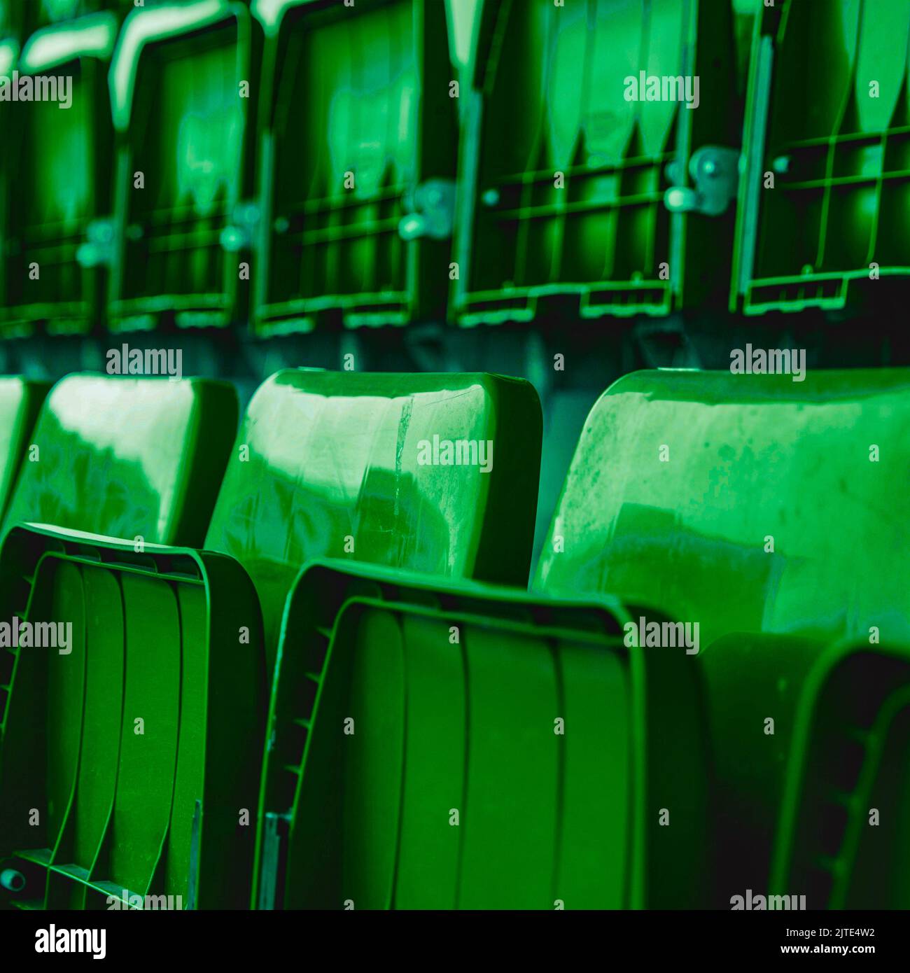 Vue latérale des sièges pliants en plastique vert du stade pour le public. Le cliché est sans marque ni personne. Banque D'Images