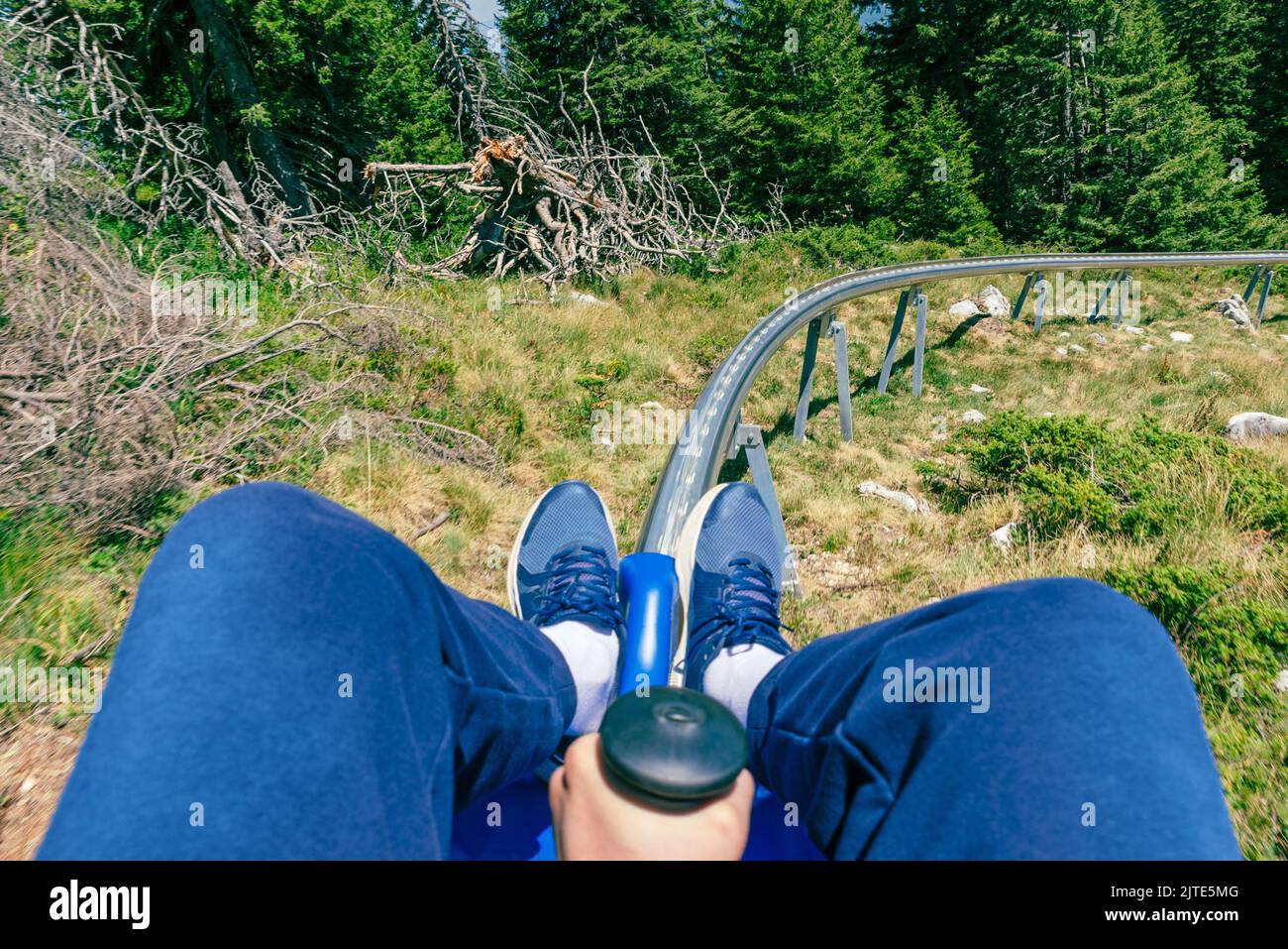 Montagnes russes première personne. Guy maintient le levier de frein. Ligne de chemin de fer et arbres devant Banque D'Images