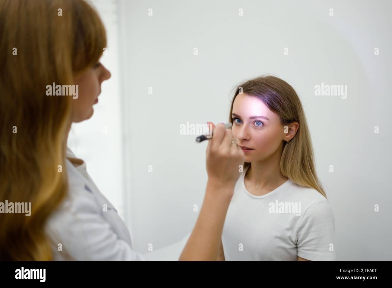 Jeune femme en nomination neurologue. Une femme médecin vérifie les réflexes des yeux avec une lampe de poche Banque D'Images