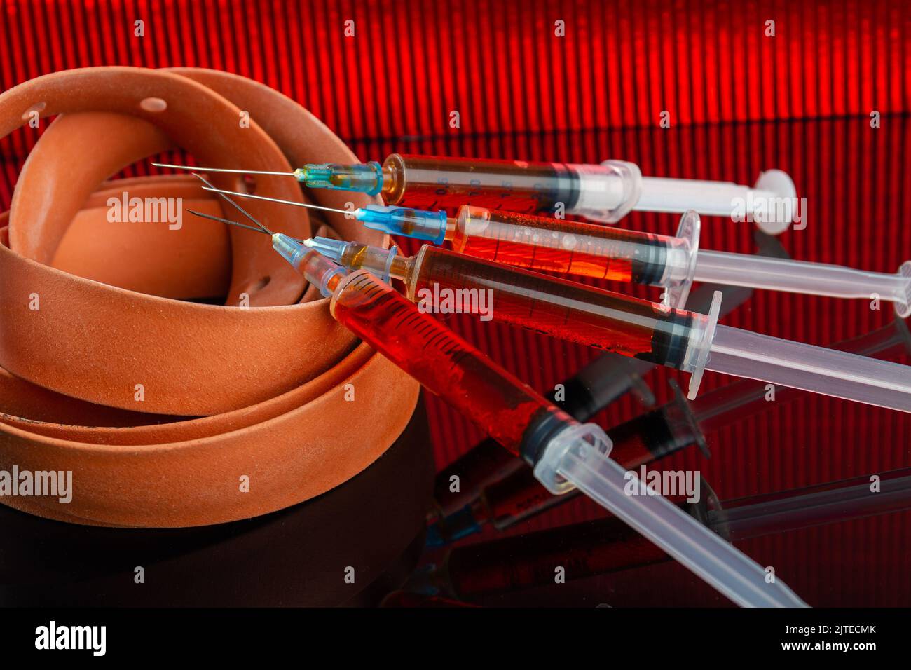 De nombreuses seringues remplies de liquide et de tourniquet torsadé. Concept d'injection de drogues. Banque D'Images