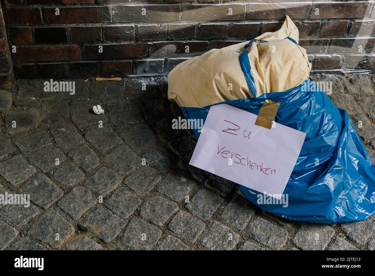 Un coussin dans un sac poubelle se trouve sur le côté de la route avec l'inscription « à donner Banque D'Images