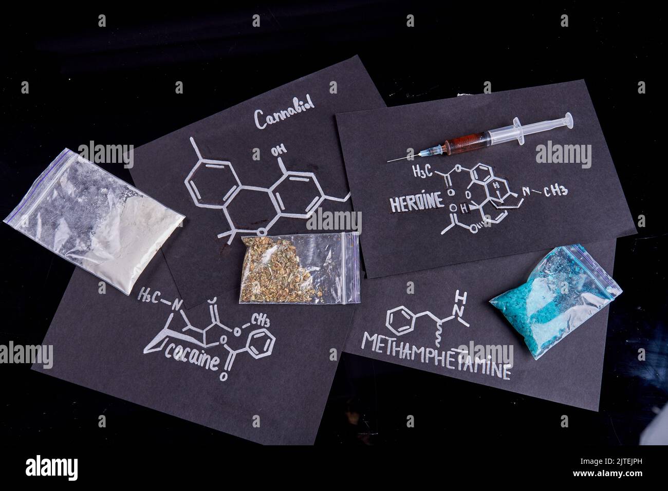 Vue de dessus molécules de médicaments et emballages en plastique isolés sur fond noir. Méthamphétamine cocaïne héroïne et cannabiol. Banque D'Images