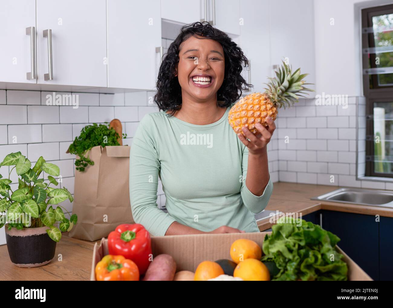 Une jeune femme végétalienne tient un ananas avec livraison de fruits et de boîtes de légumes Banque D'Images