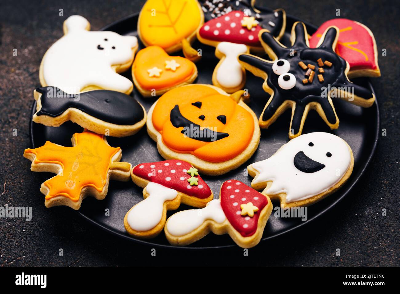 Biscuits au sucre d'Halloween avec glase sur fond marron foncé - citrouille, champignons, chat noir, fantômes, araignée, batte. Gros plan Banque D'Images