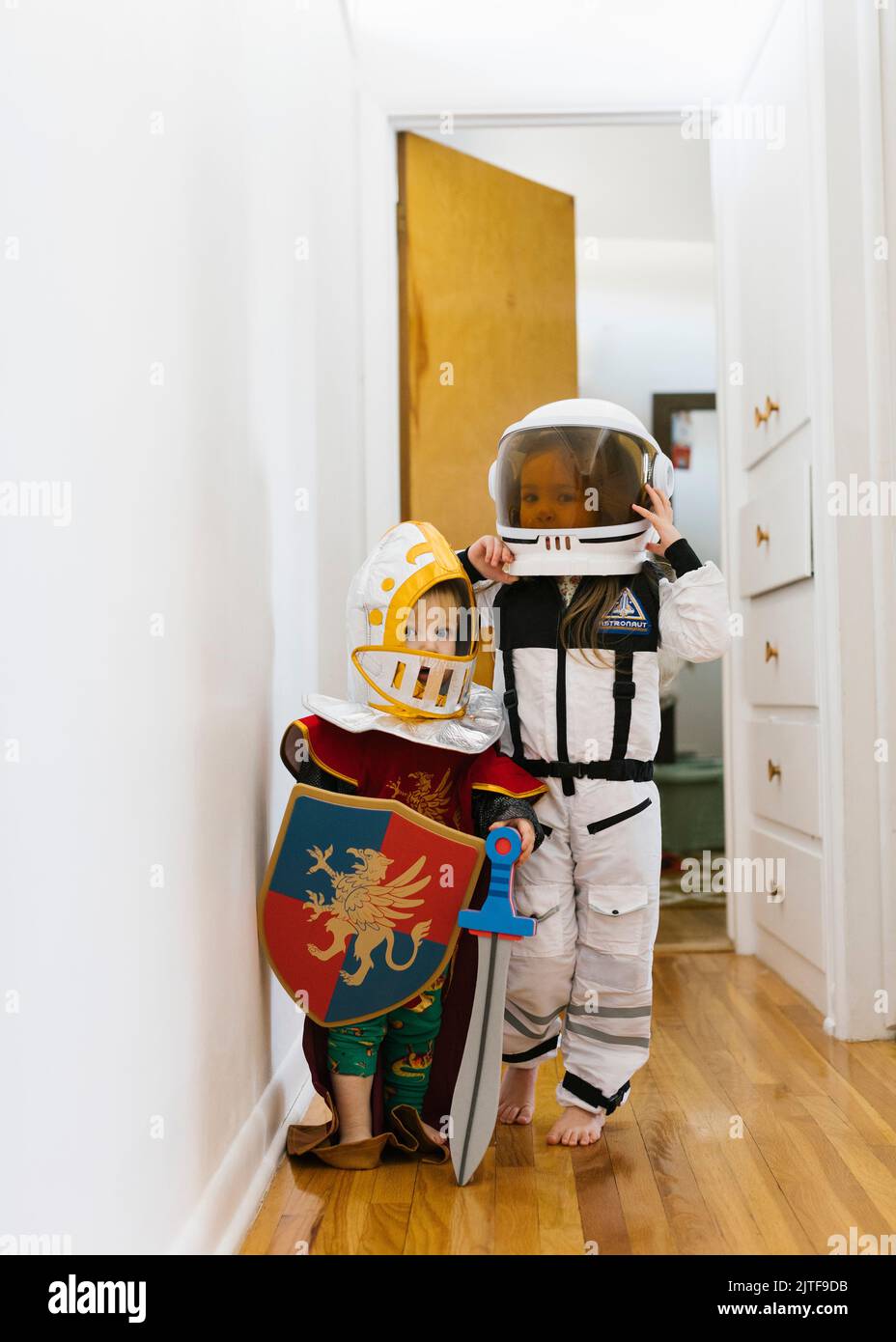 Jeune garçon (2-3) en costume de chevalier et fille (2-3) en costume d'astronaute jouant à la maison Banque D'Images