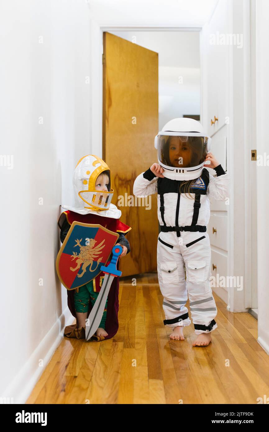 Jeune garçon (2-3) en costume de chevalier et fille (2-3) en costume d'astronaute jouant à la maison Banque D'Images