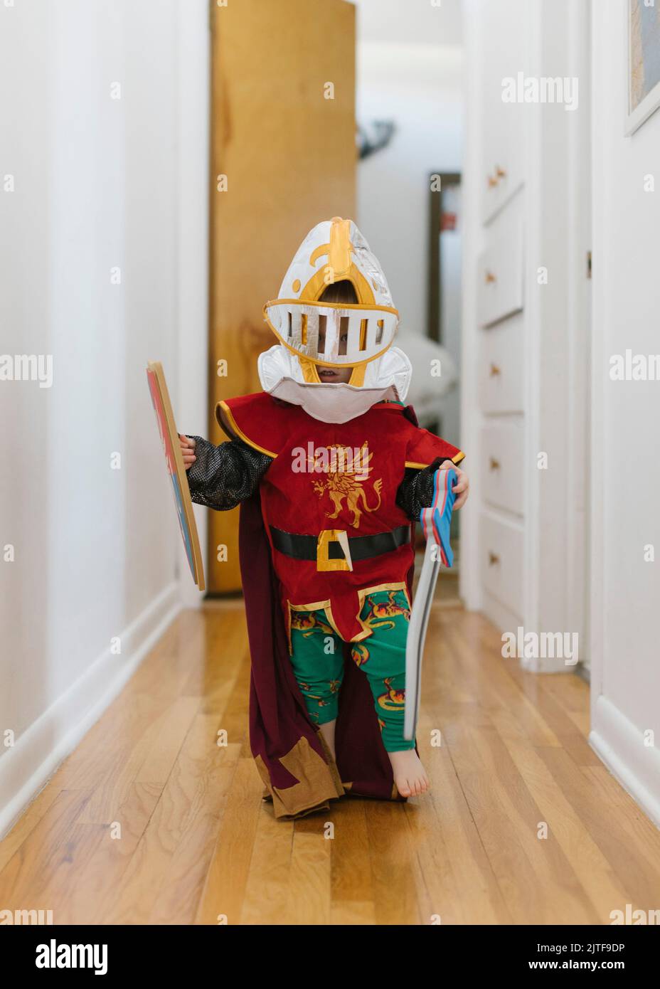 Tout-petit garçon (2-3) en costume de chevalier jouant à la maison Banque D'Images