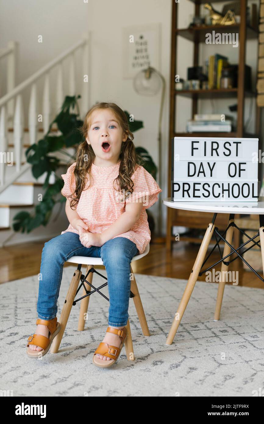 Portrait d'une fille (2-3) faisant des visages au premier jour du signe préscolaire Banque D'Images